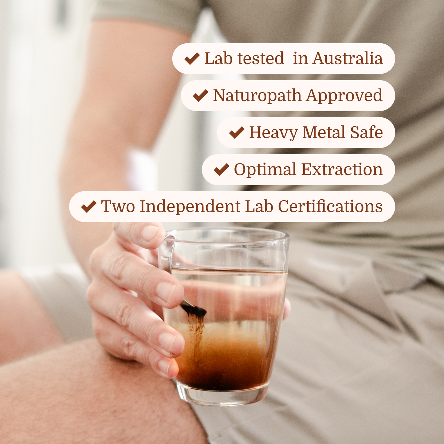 man holding shilajit resin dissolving in a glass of water