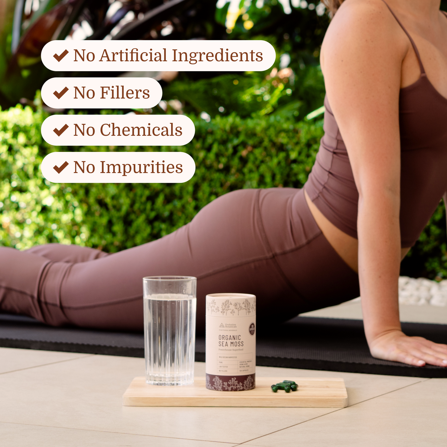 sea moss capsules on a chopping board while a women is doing yoga behind it
