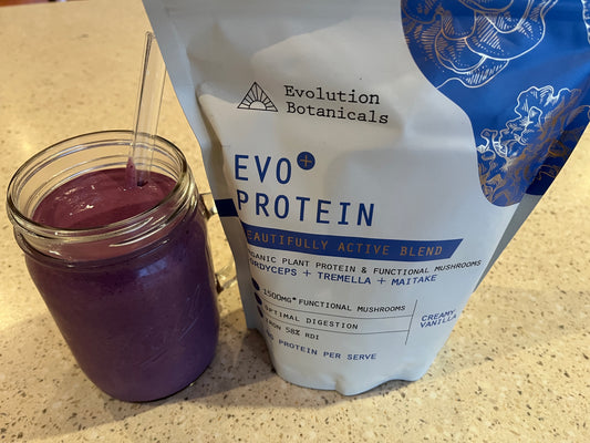 The finished Vanilla Berry Protein smoothie in a glass jar next to a bag of Evo+ Protien Creamy Vanilla 