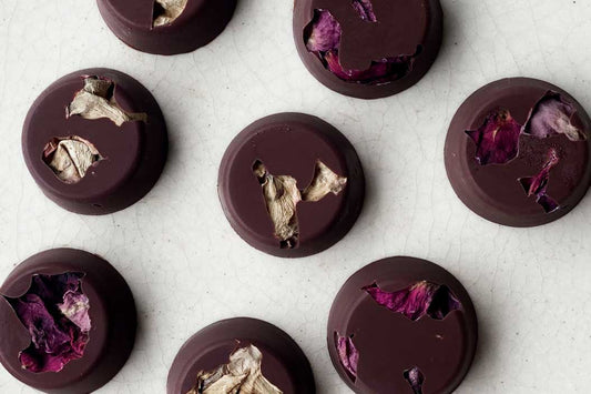 A top down shot of 8 finished rose and ginger  dark chocolates with mushrooms in them .