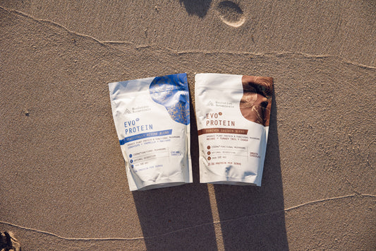 A topdown shot of Evo+ Protein range sitting on concrete, including products: Creamy Vanilla and Smooth Chocolate. 