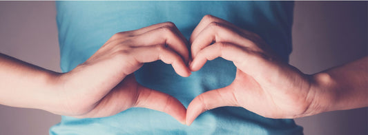 A close up shot of a person's hands making a heart shape with their fingers