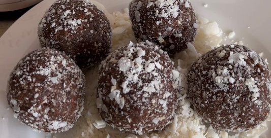 5 chocolate peanut butter protein balls sitting in a bowl.