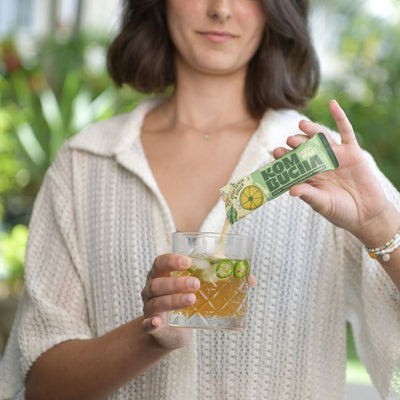 Woman pouring Ready Set Kombucha into a glass of water